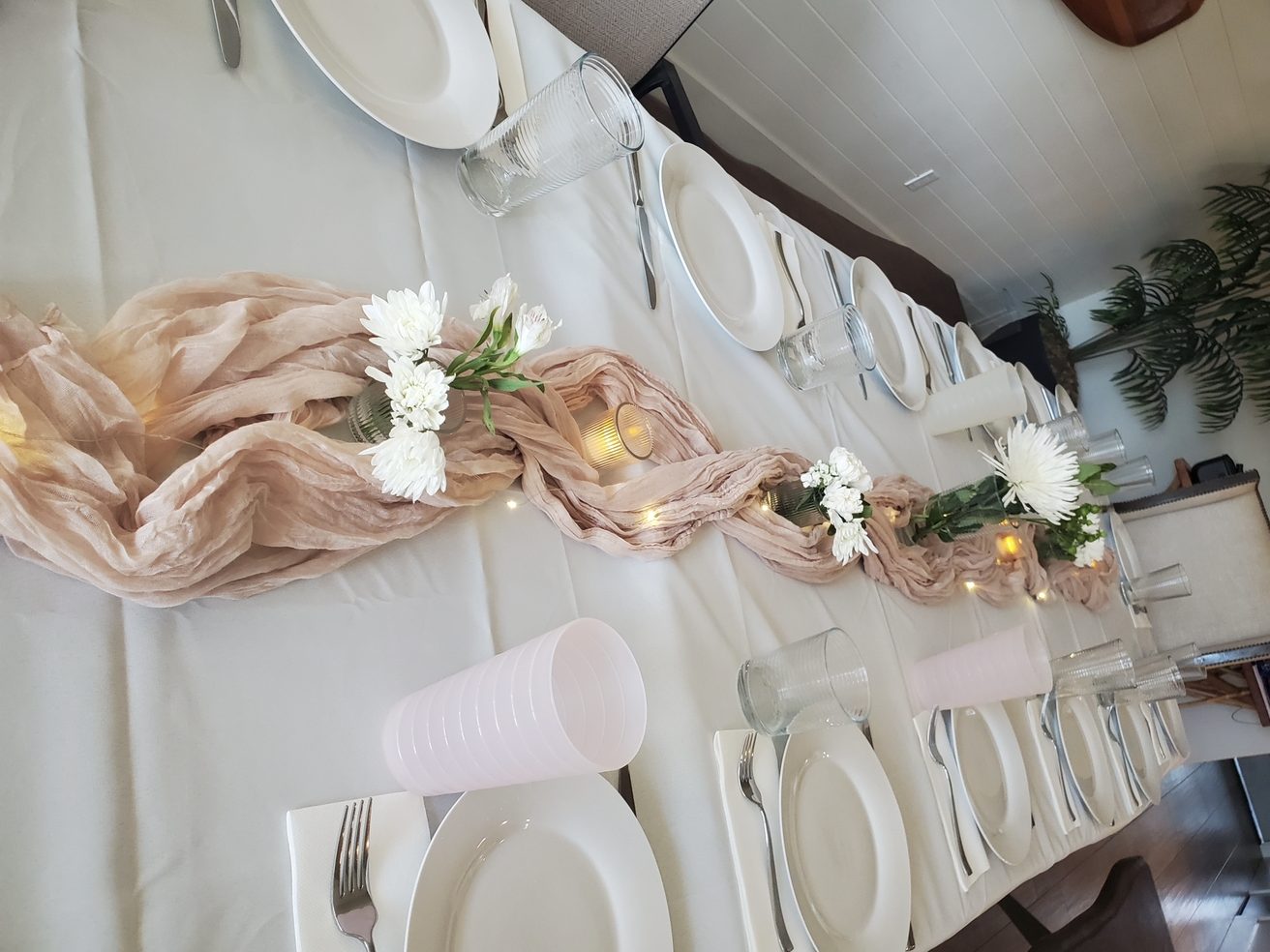 A table dressed with a blush runner, white flowers and folded napkins
