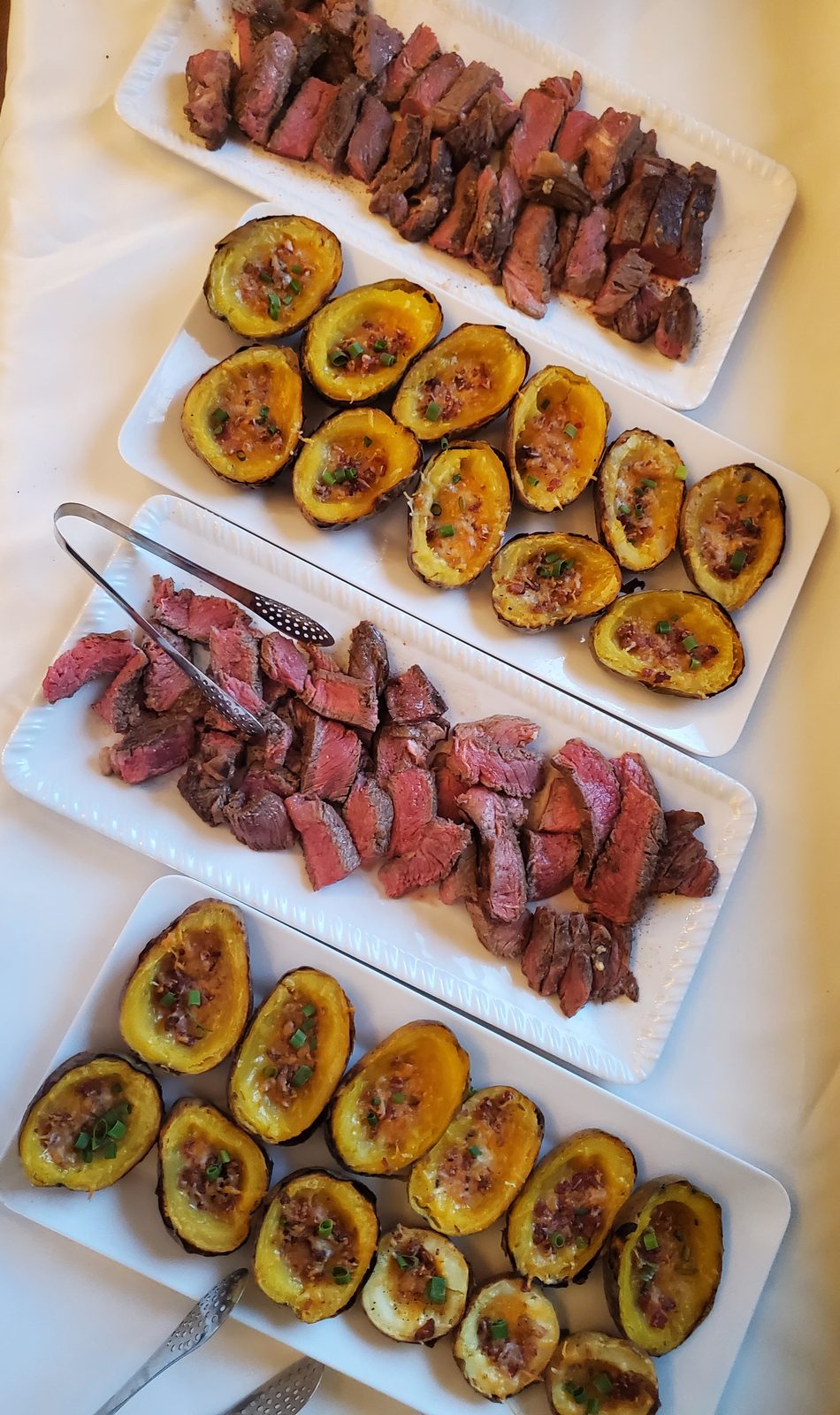 Sliced steak and roasted eggplant on long platters