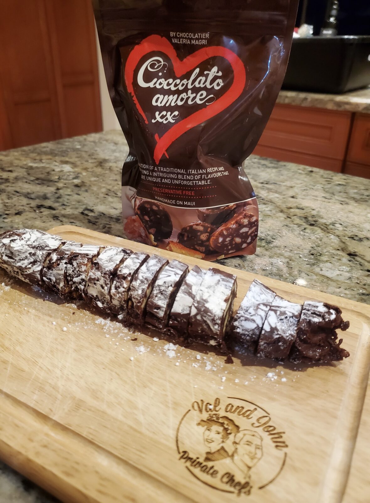 Cioccolato Amore chocolate salami, sliced on a Val and John board, with its bag behind