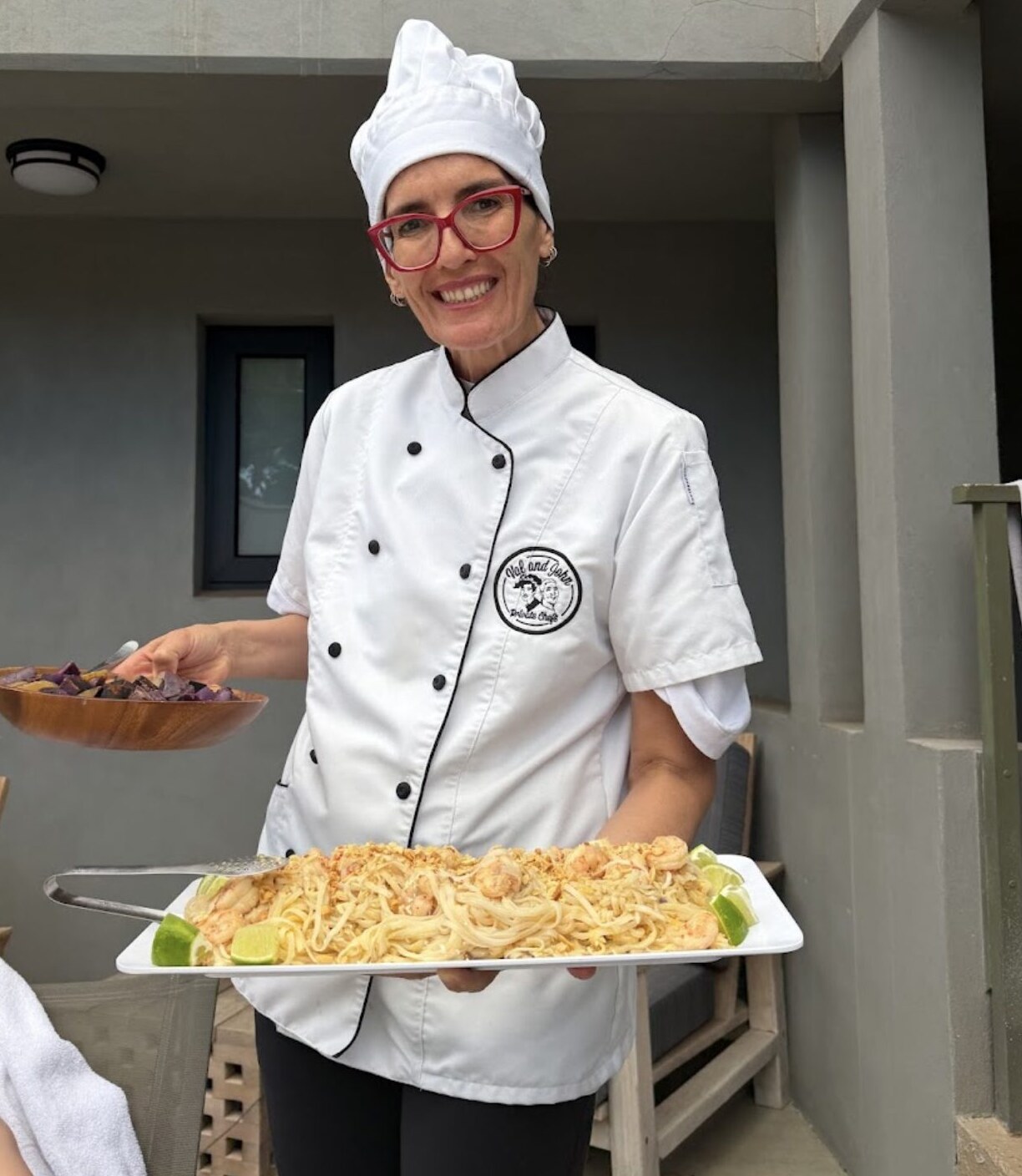Val in chef whites holding a tray of pasta